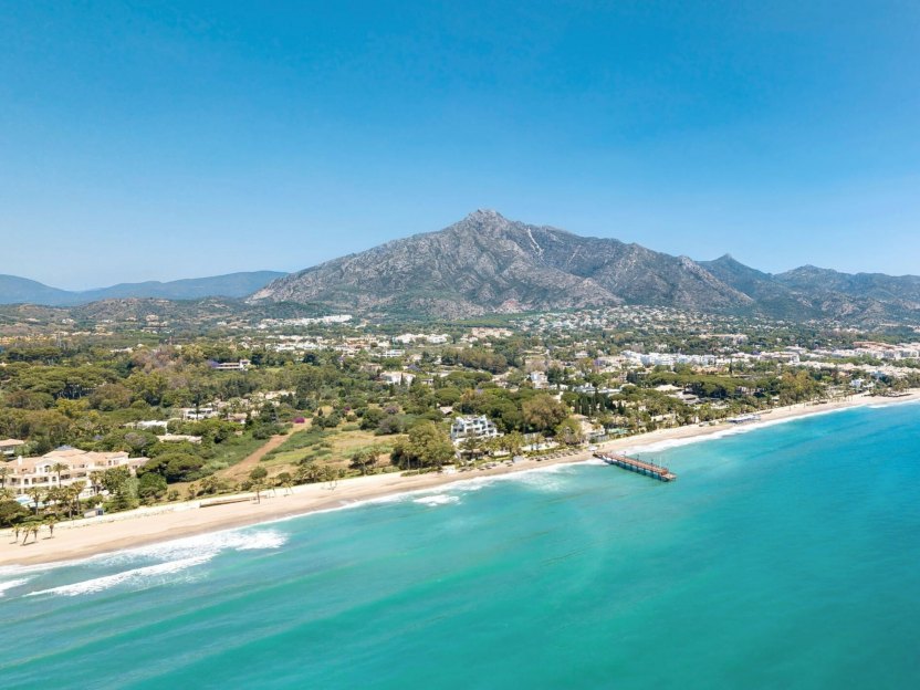 Aerial view of Marbella, showcasing the beaches along the coast and Sierra Blanca mountains in the background.