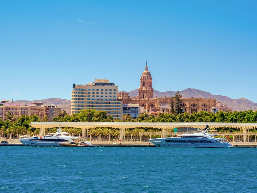 View of Malaga from the sea, showcasing Muelle Uno and the Malaga Cathedral in the background.