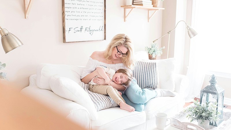 a mother and her son playfully sitting in the living room they personalized as one of the tips after buying a house