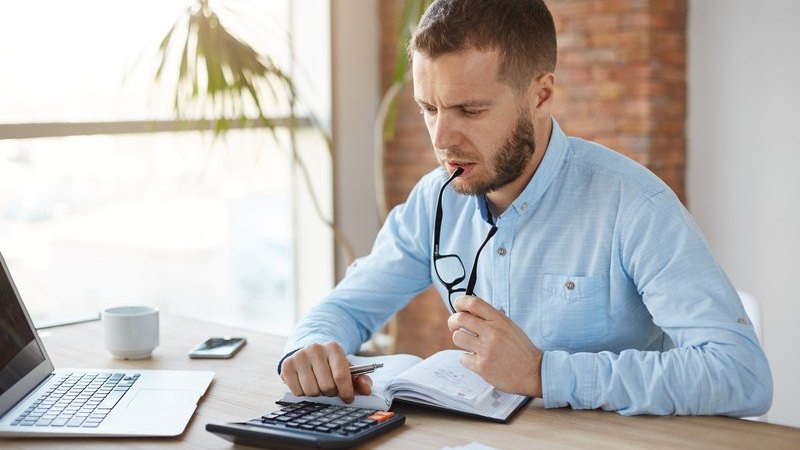 man working on his taxes, featured image for the article