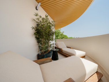 Outdoor lounge area with modern white cushions and bamboo plant