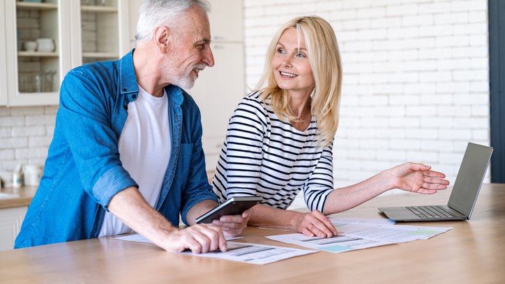 Mature wife and husband checking documents with tax, pension savings and internal bills. Doing payments online and discussing family budget. Calculating funds for purchase new home