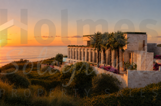 La Roca de San Diego is a contemporary three-level villa crafted from honed travertine and floor-to-ceiling glass, with panoramic south-facing views across the Mediterranean to Gibraltar and Africa