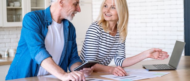 Mature wife and husband checking documents with tax, pension savings and internal bills. Doing payments online and discussing family budget. Calculating funds for purchase new home