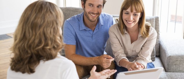 a group of people sitting around a table looking at a tablet