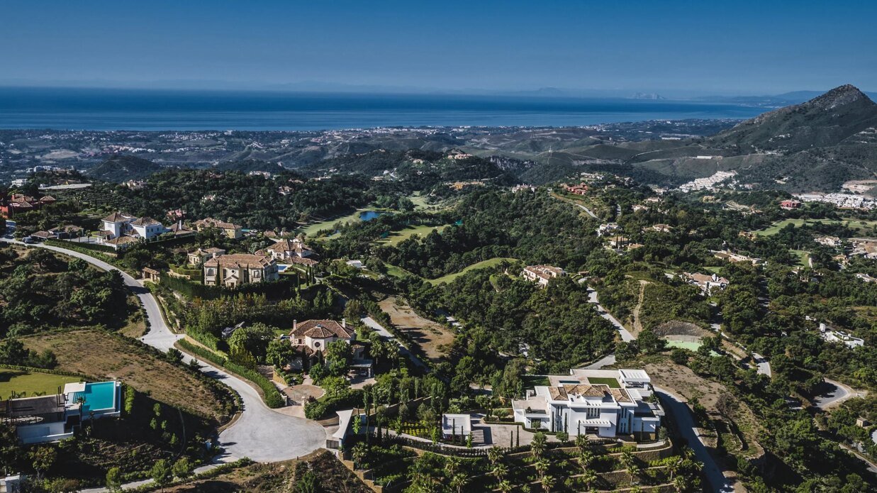 Aerial view of luxury villas in Marbella’s hillside prime residential areas surrounded by greenery and golf courses.
