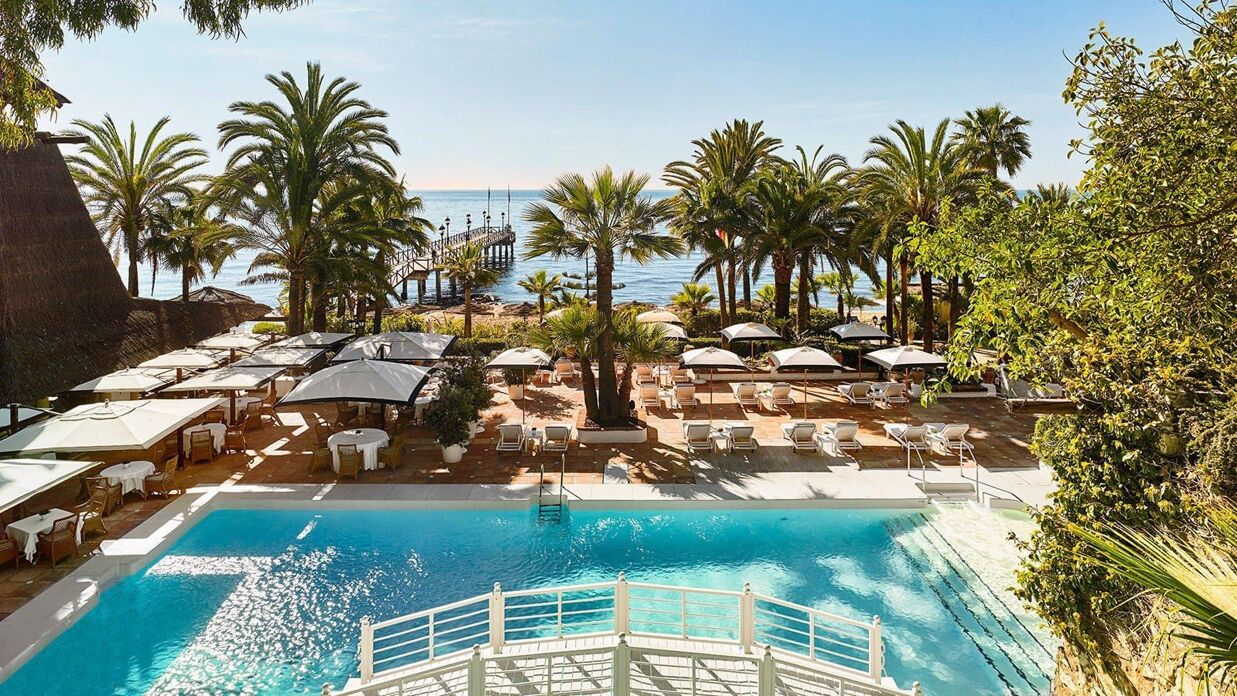 Tidlös elegans vid havet – Marbella Clubs ikoniska beach club med vita parasoller och mjuka vågor skapar en fristad av lyx och stillhet.