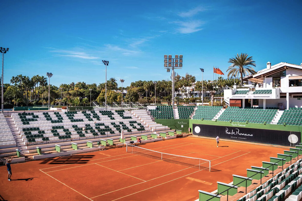 The iconic center court of Puente Romano Tennis Club, featuring its name through the coloured seats