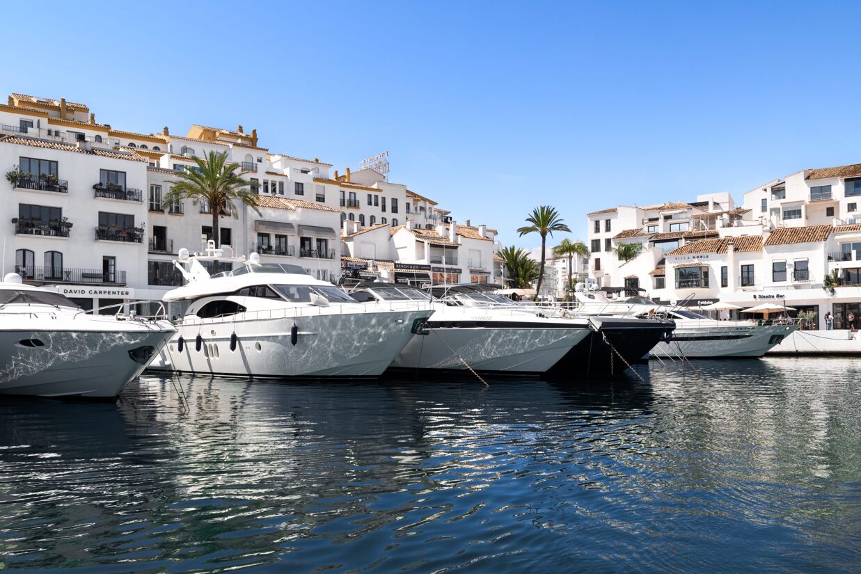 Luxury marina in Marbella with yachts and white Andalusian-style buildings.