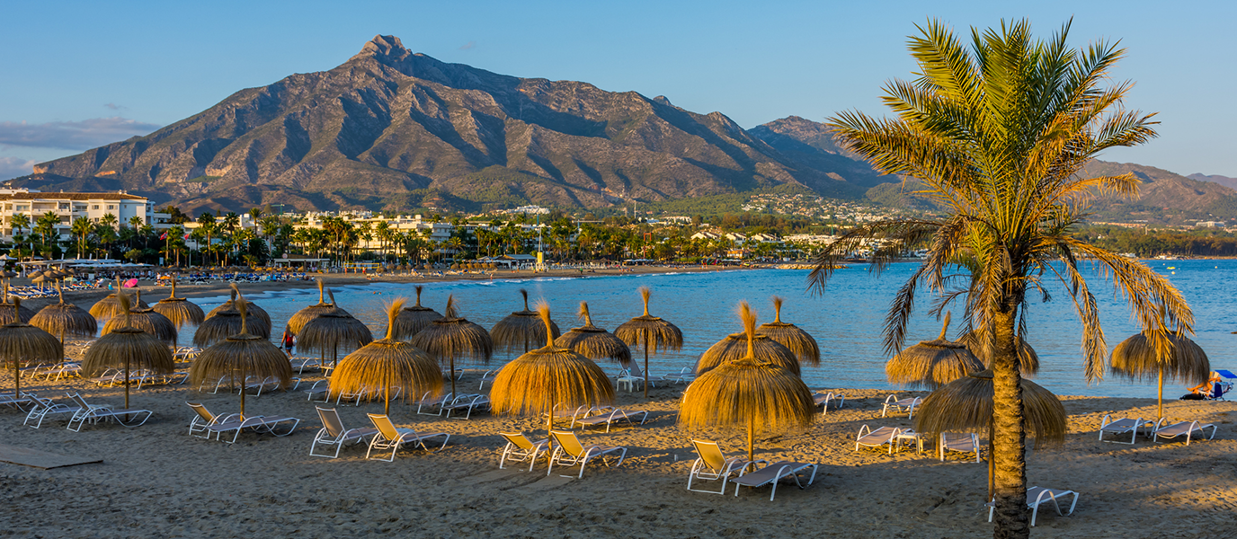 Scenic Marbella coastline bathed in golden sunset light with the Mediterranean horizon.