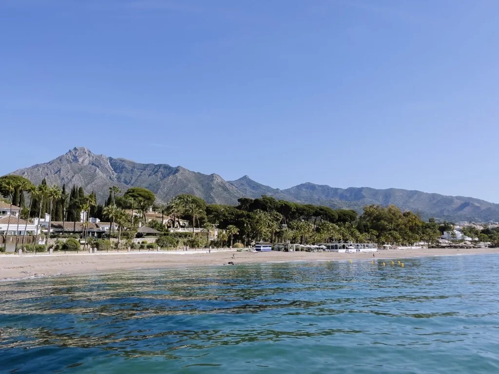 Archival black-and-white image of Marbella Club’s early days paired with a modern photo of a Golden Mile villa terrace overlooking the sea.