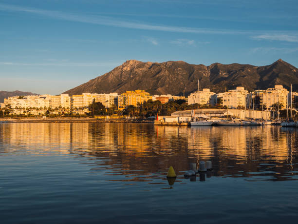Autumn sunset view of Marbella with golden sky and Sierra Blanca mountains in the background.