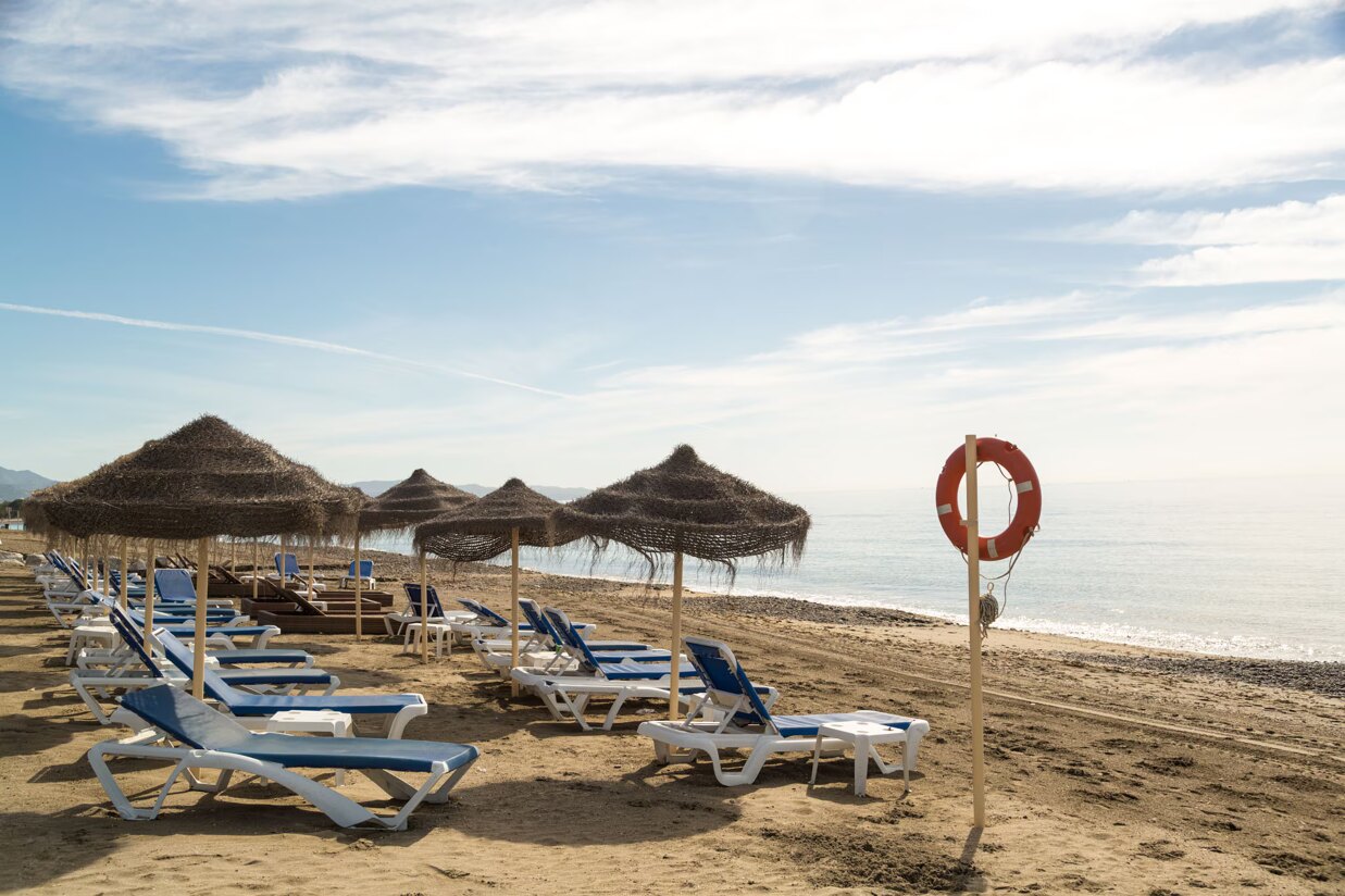 Sun loungers and umbrellas on San Pedro Playa beach with calm sea view