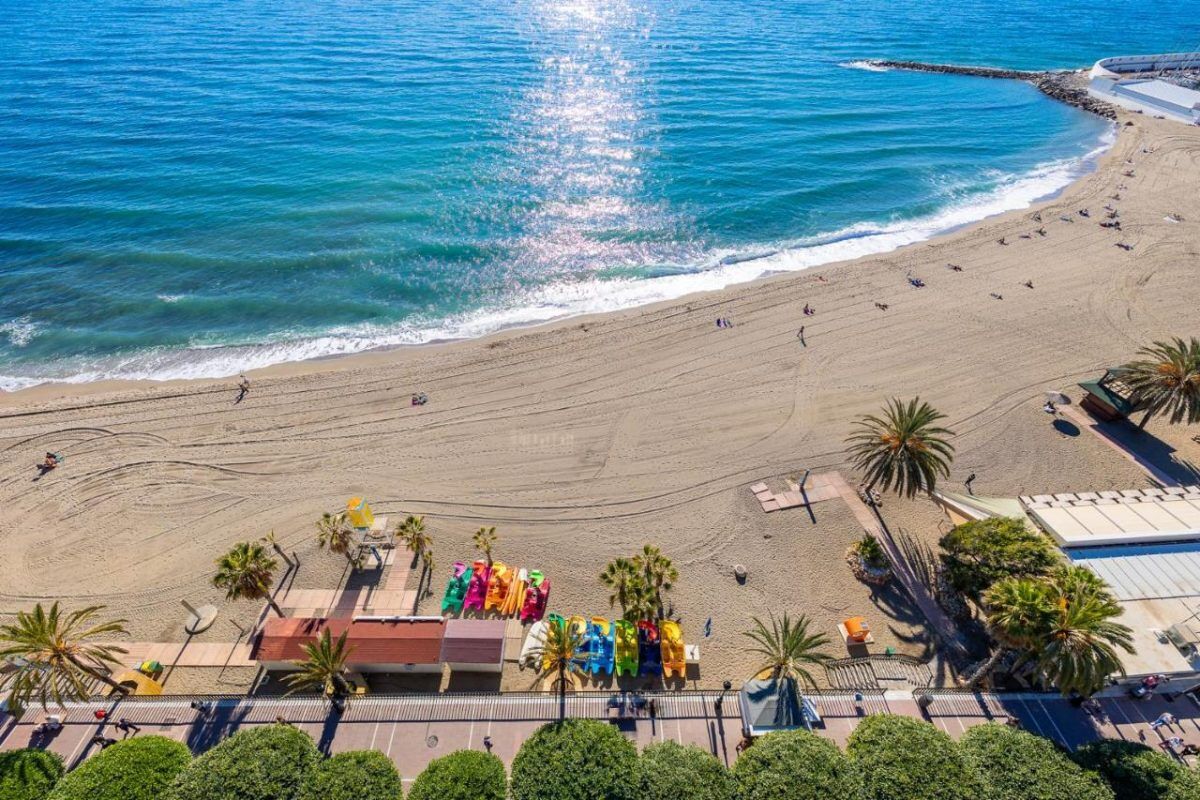 Flygvy över San Pedro Plajas strandpromenad och strand, där modernt boende möter havet.