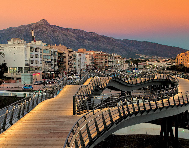 San Pedro Boulevard pedestrian bridge at sunset with city buildings and mountains