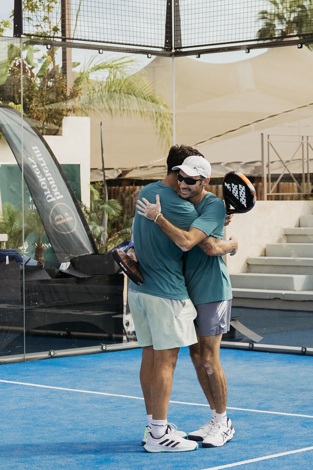 Men's padel team embracing in celebration after securing their place in the final at the Homerun Brokers tournament in Marbella.
