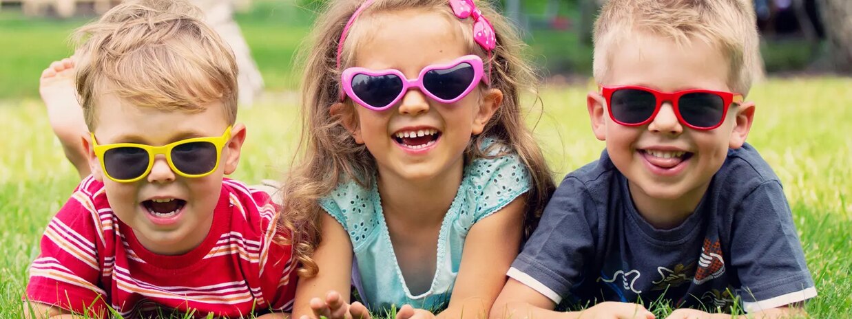 kids smiling wearing glasses laying on the grass