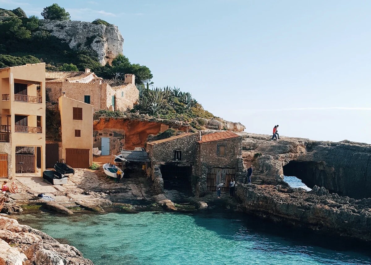 Traditional stone houses and turquoise cove on Mallorca’s southwest coast, showing rustic Mediterranean charm