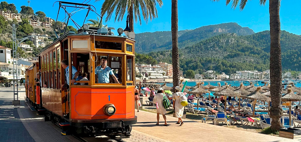 The Sóller tram crossing orange groves with the mountains in the background.