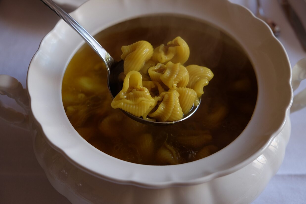 A close-up of traditional Mallorcan Christmas food, such as Sopa de Nadal and Escaldums, served at a family dinner.