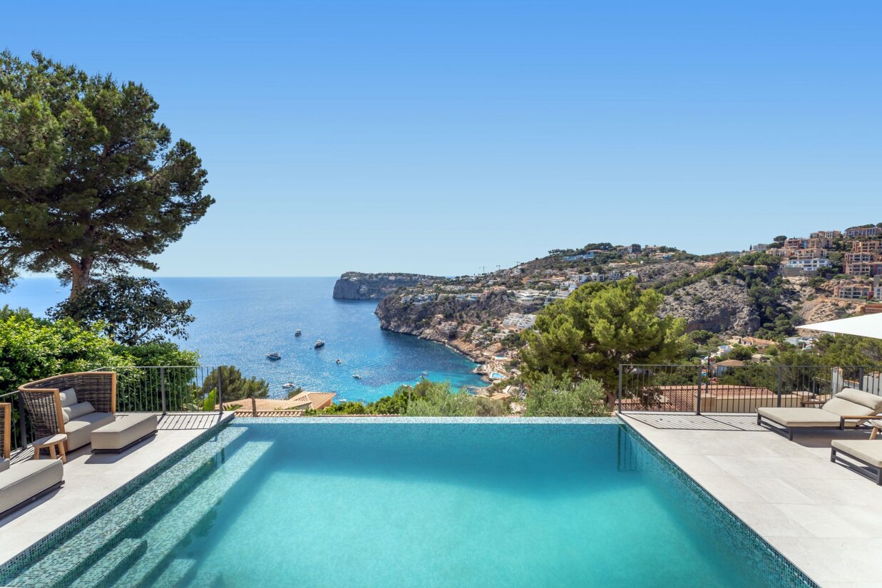 Infinity pool with sea views in Port d’Andratx, framed by coastal hills, villas, and boats on the bright blue water.