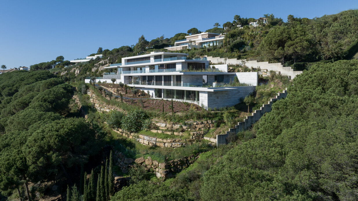 Modern luxury villa in La Reserva Sotogrande with sea views, large glass windows, landscaped gardens, and contemporary architecture integrated into nature.