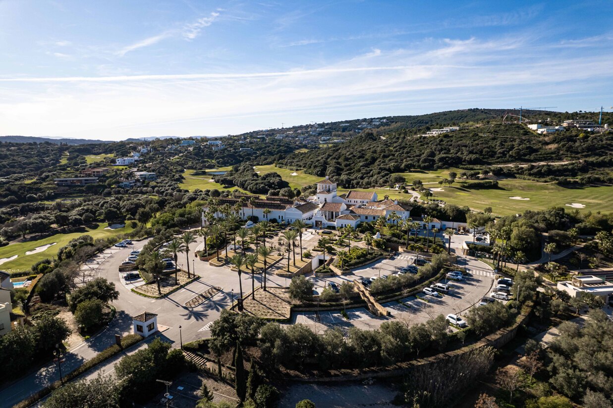 Aerial view of La Reserva de Sotogrande golf course and luxury residential area surrounded by hills and Mediterranean landscape.