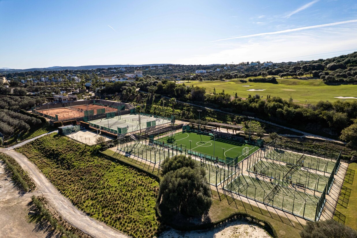 Aerial view of tennis and padel courts in Sotogrande surrounded by greenery and golf landscape.