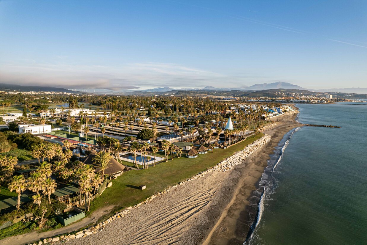 Aerial view of Sotogrande coastline with beach, palm trees, and La Reserva Club facilities.