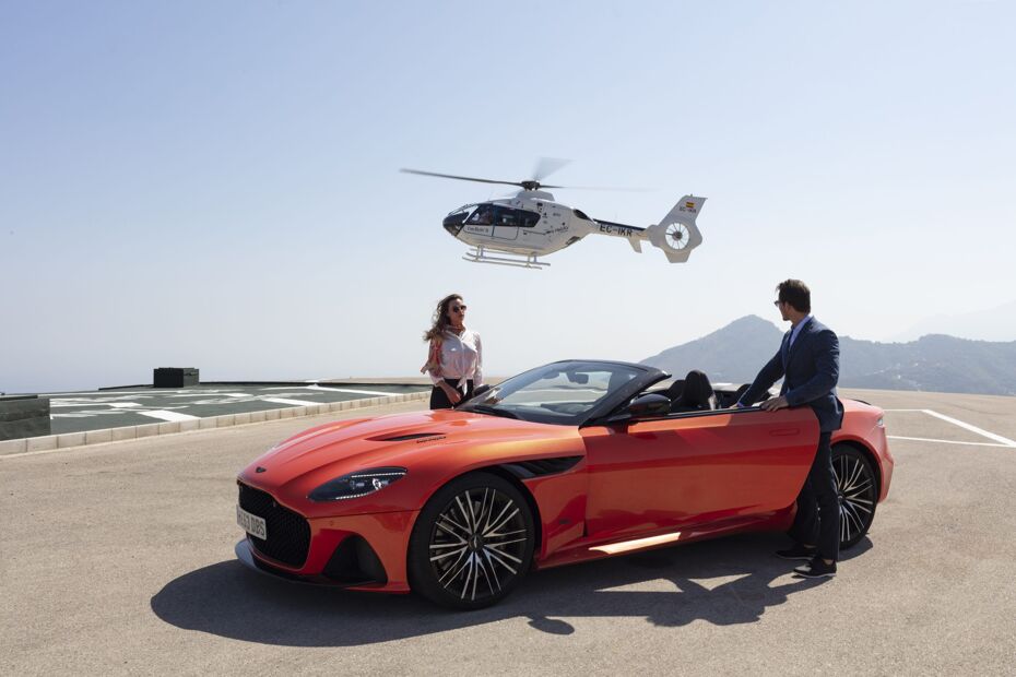 Photograph of a couple exciting a sports car with a private helicopter landing in the background in Marbella