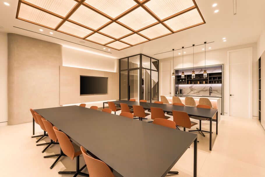 Inside Drumelia – multi-purpose kitchen and events space with black tables, orange chairs, and marble bar in Marbella office