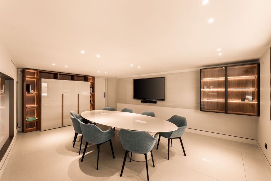 Inside Drumelia – private meeting room with oval white table, blue chairs, and built-in storage in Marbella office