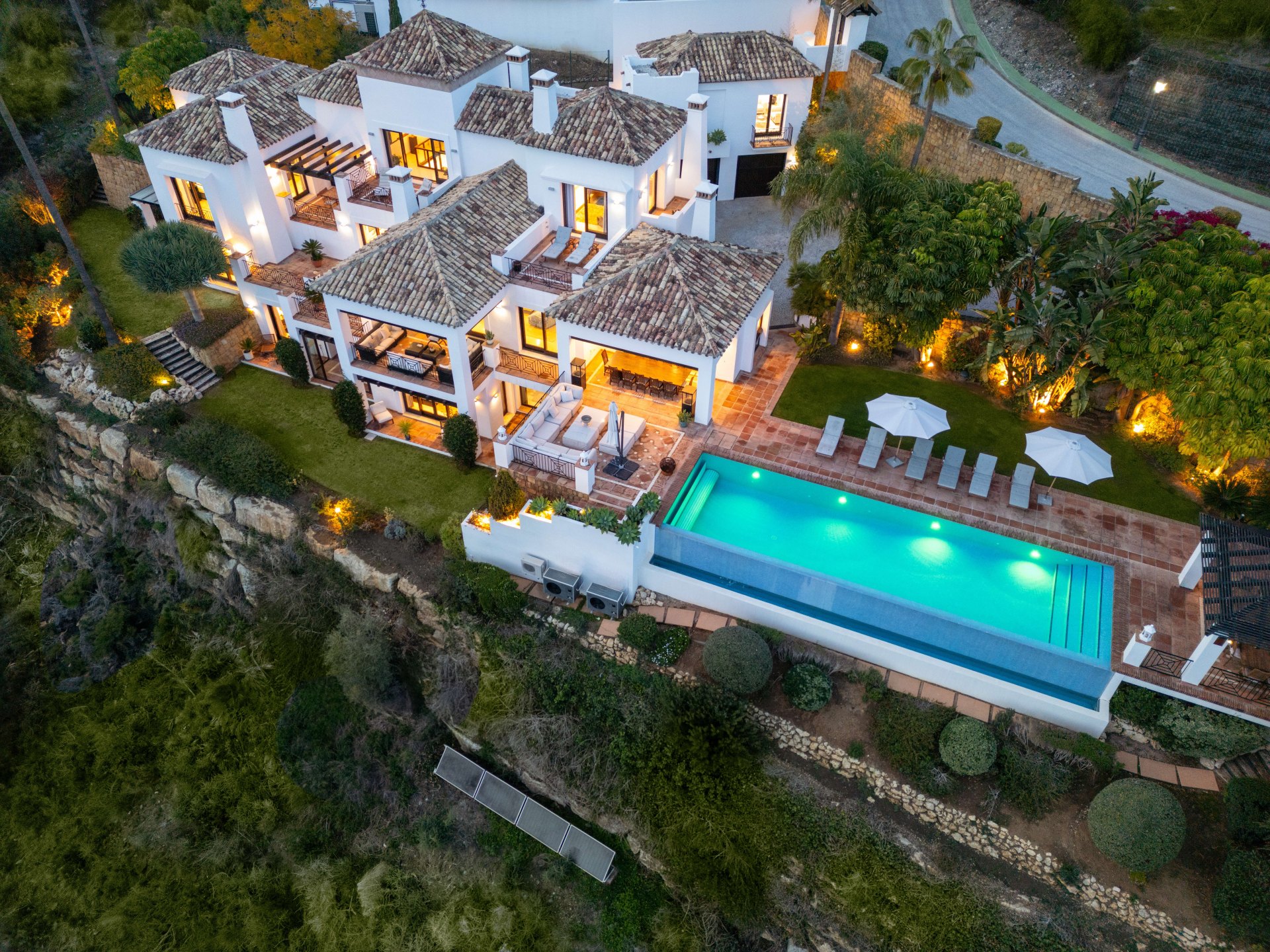 Hilltop villa in La Quinta, Benahavís, featuring Andalusian architecture, warm lighting, and an infinity pool overlooking nature.