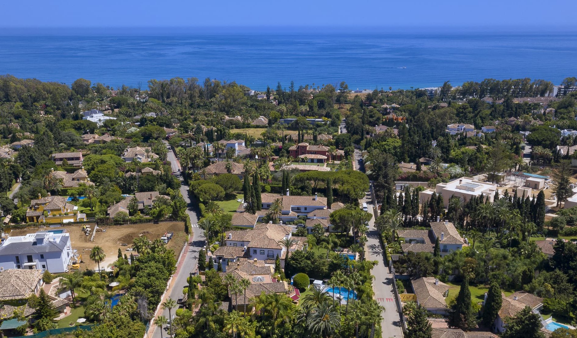 Aerial view of Guadalmina, Marbella, showcasing lush greenery, elegant villas, and the Mediterranean Sea in the background.