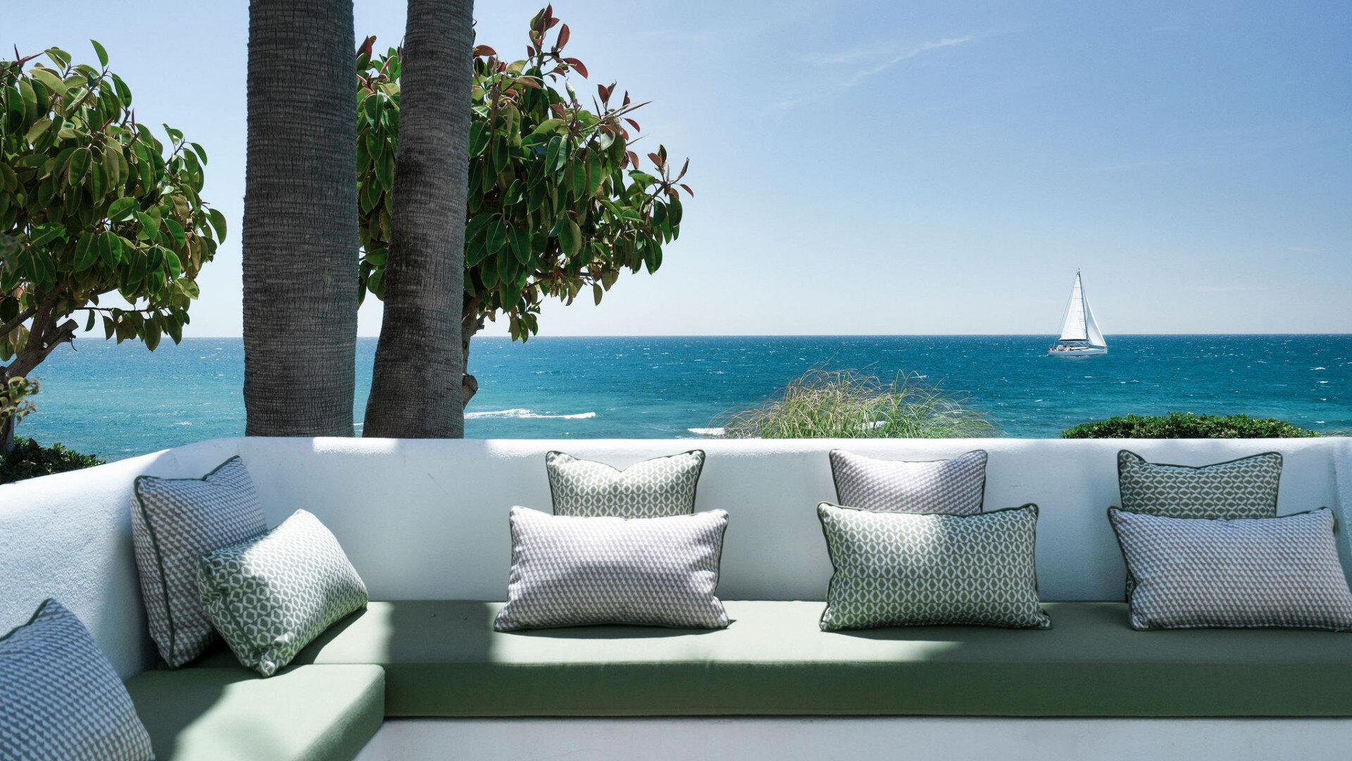 A balcony with stunning Mediterranean views and a sailboat on the horizon