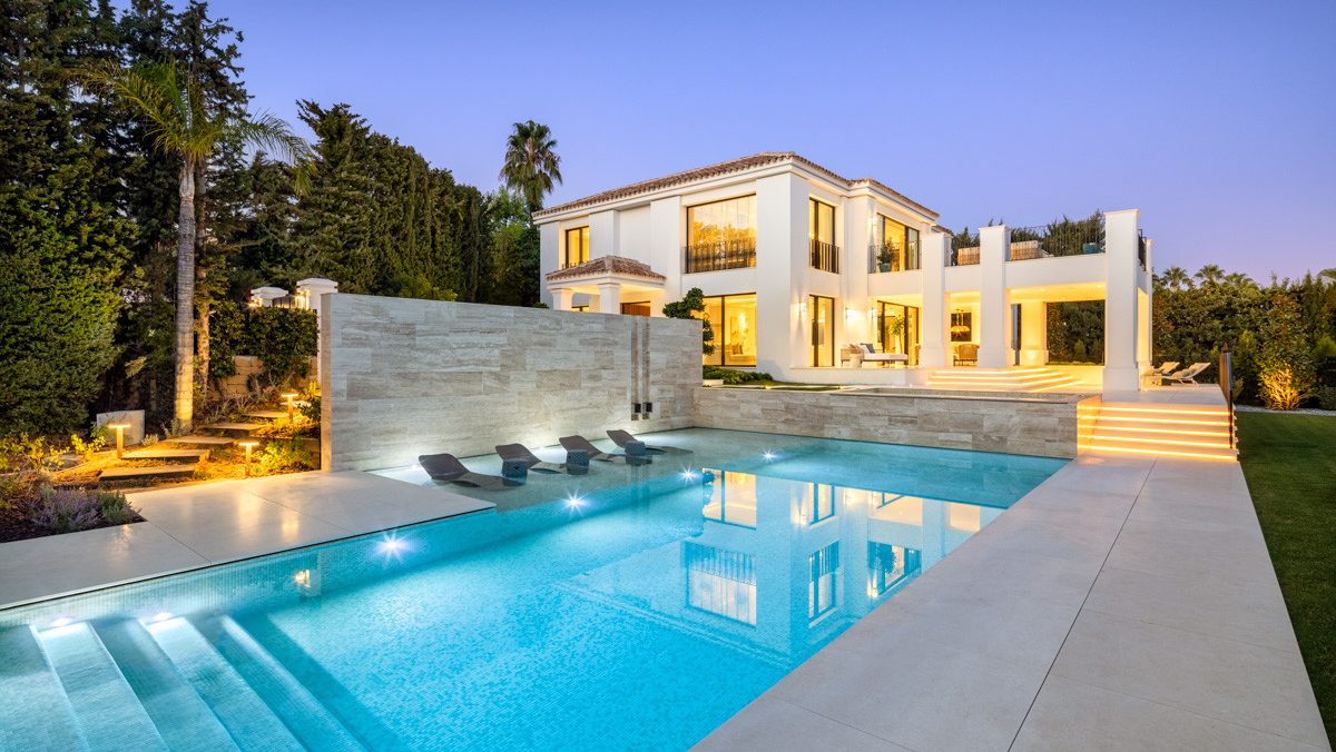 Contemporary villa in Sierra Blanca, Marbella, with a cascading pool, ambient lighting, and elegant architecture set against lush greenery.