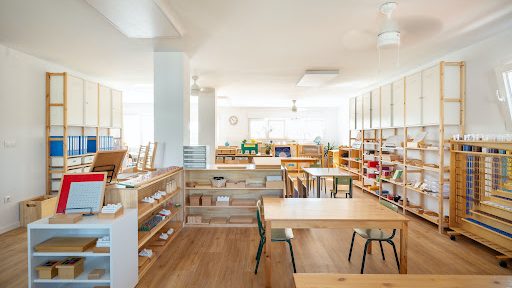 Bright Montessori classroom with wooden shelves, child-sized furniture, and hands-on learning materials.