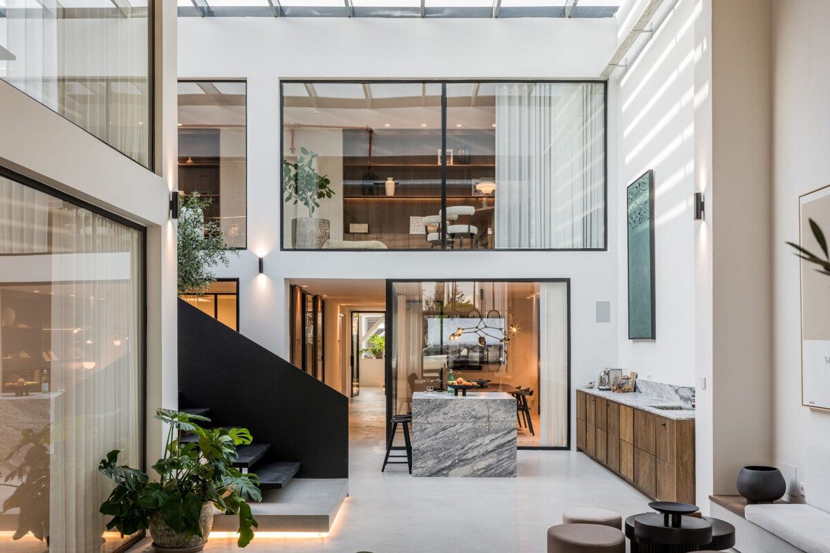 Norma Franck office in Marbella, featuring a modern double-height interior with floor-to-ceiling windows, sleek black staircase, and elegant natural finishes.