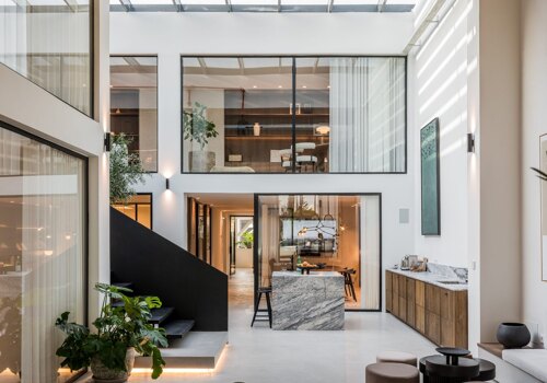 Norma Franck office in Marbella, featuring a modern double-height interior with floor-to-ceiling windows, sleek black staircase, and elegant natural finishes.