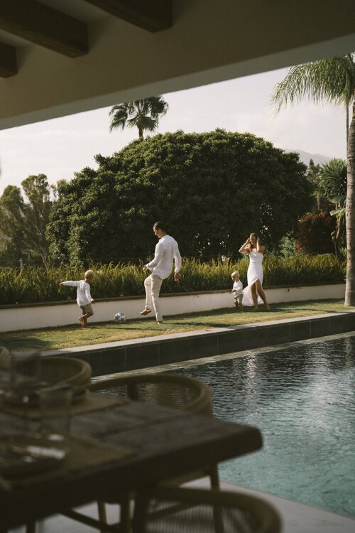 Villa Nazari. Family enjoying outdoor living in a Marbella villa, playing by the pool with lush greenery and mountain views in the background.