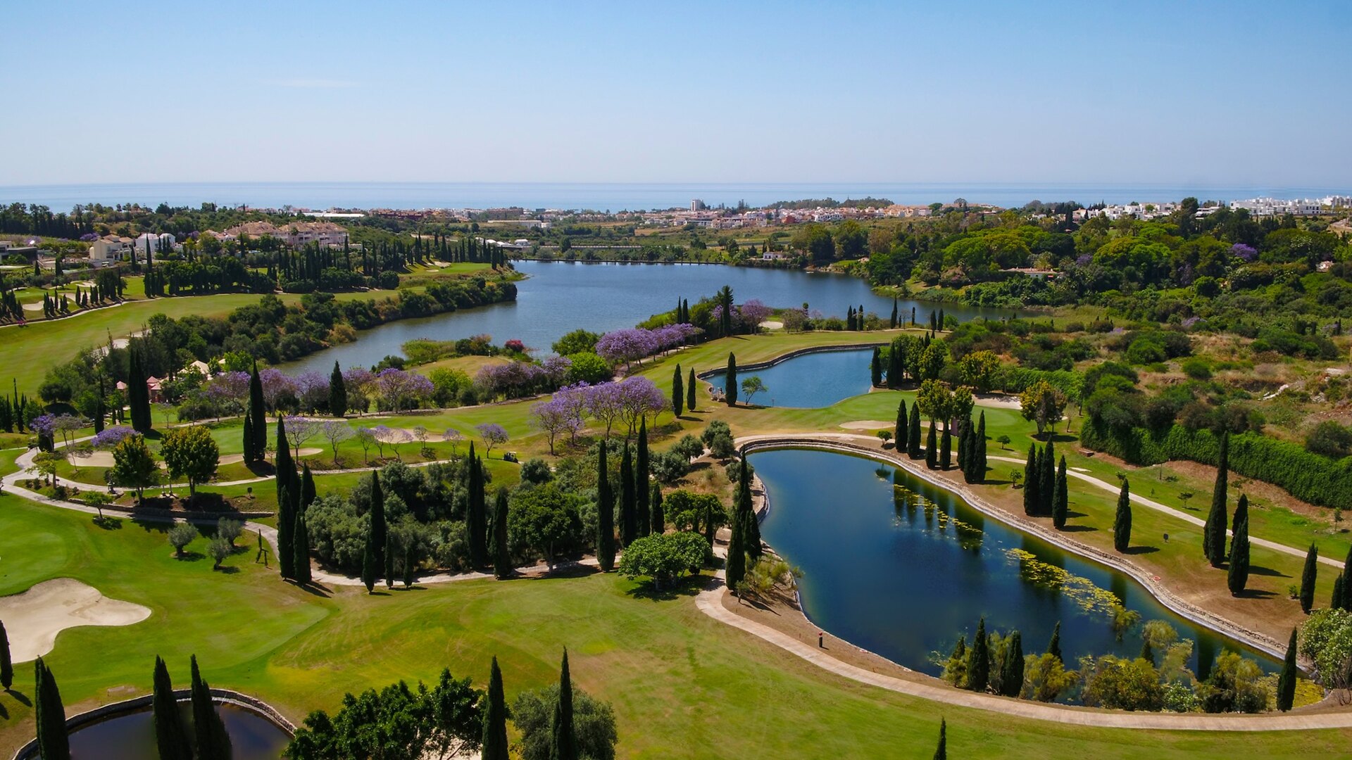 Aerial view of Villa Padierna in Marbella, featuring a lush golf course, serene lakes, and Mediterranean Sea views.