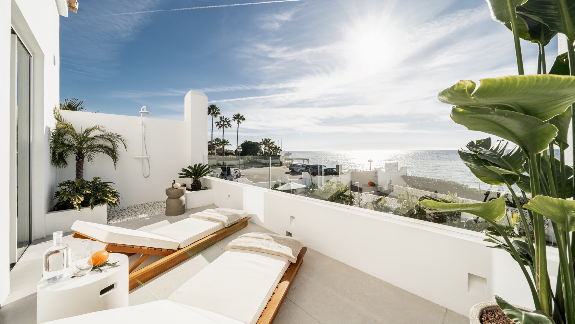 Private terrace in Los Monteros with sun loungers, tropical plants, and a sea view, bathed in natural sunlight.