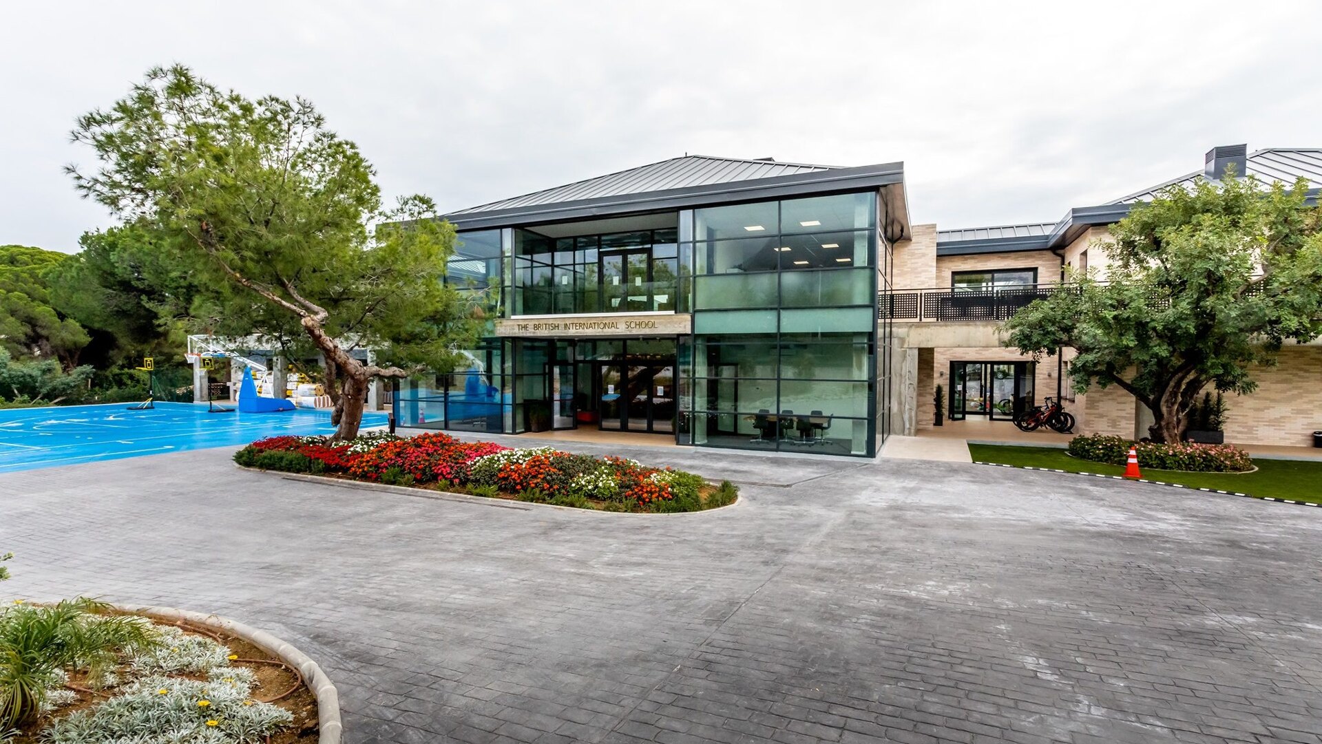 The British International School in Marbella, featuring a modern glass facade, landscaped entrance, and outdoor sports facilities.