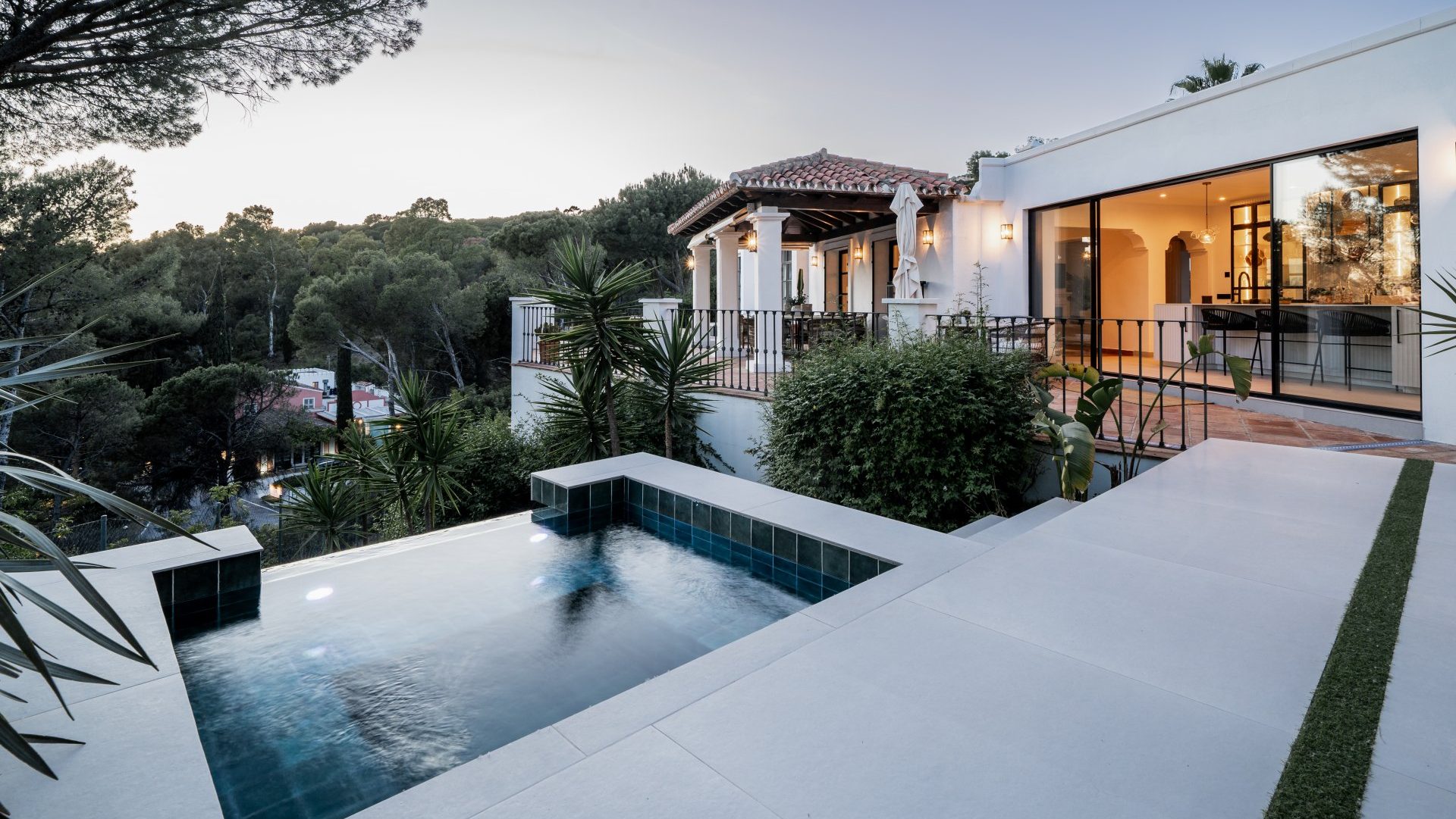 Villa in El Madroñal, Marbella, featuring a private plunge pool, Andalusian-style architecture, and lush forest views at dusk.