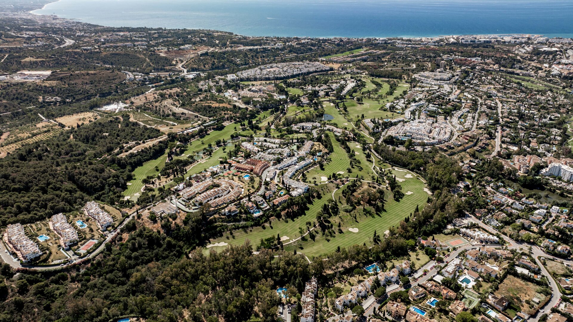 Aerial view of Nueva Andalucía, The Golf Valley of Marbella, with lush fairways, residential developments, and the Mediterranean coastline in the background