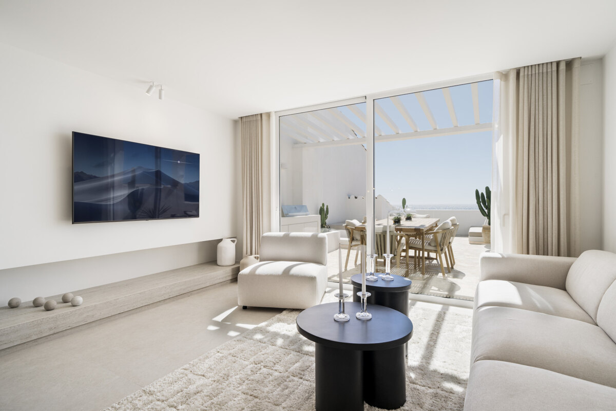 Bright apartment in Puerto Banús with a modern living room, white sofa, neutral decor, and a spacious terrace with sea views.