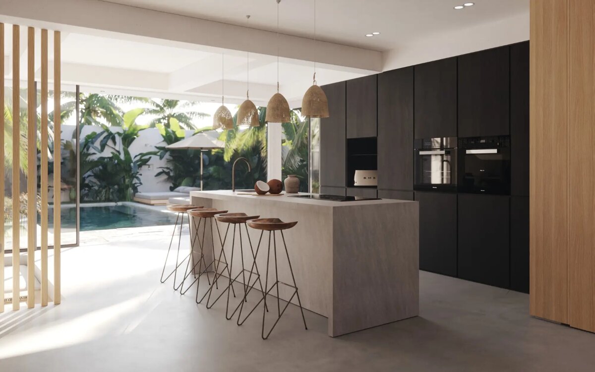 Modern open-plan kitchen with a stone island, black cabinets, rattan pendant lights, and views of a tropical garden and pool.