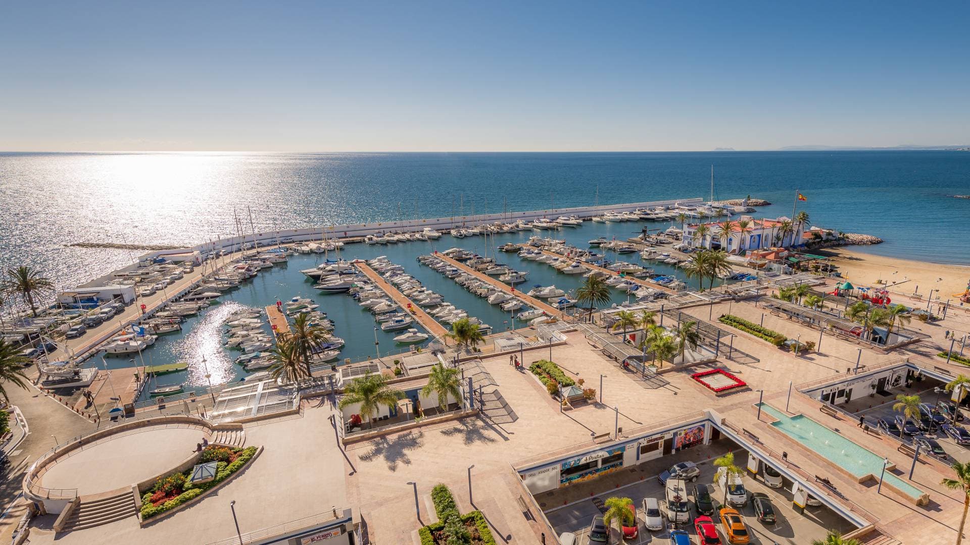 Aerial view of Marbella’s Puerto Deportivo, with yachts docked in the marina and the Mediterranean Sea in the background.