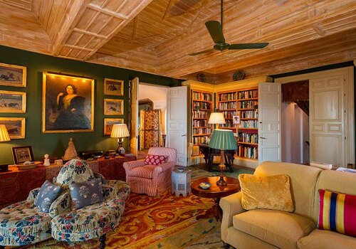 Classic living room in Alcuzcuz, Benahavís, featuring wooden ceilings, antique furniture, a library, and warm lighting.