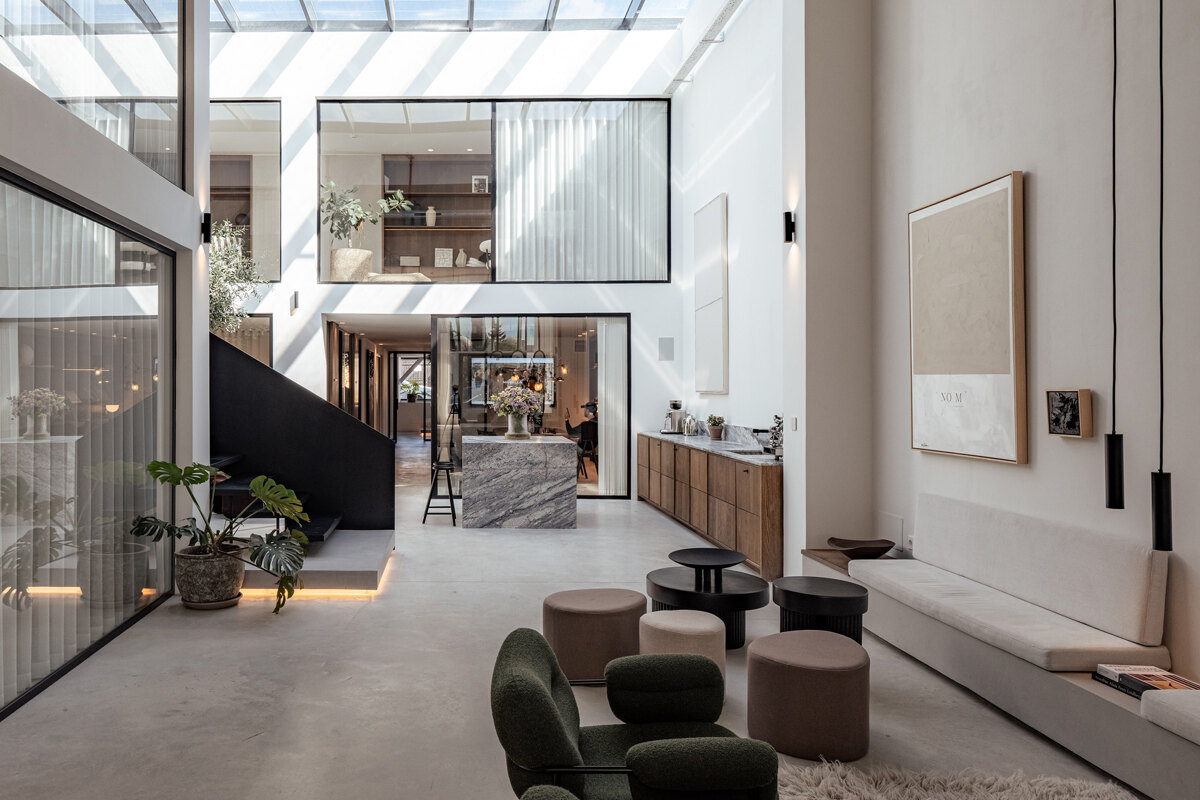 Norma Franck office in Marbella, featuring a modern double-height interior with floor-to-ceiling windows, sleek black staircase, and elegant natural finishes.